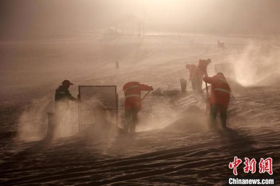 圖為敦煌市鳴沙山月牙泉景區(qū)“駱駝保姆”清理駱駝糞便?！垥粤?攝